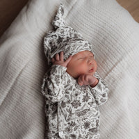 Een vredige pasgeboren baby in een rompertje met patroon en Yumi Baby's Broekje Konijntjes, heerlijk slapend op een zachte, gestructureerde deken.