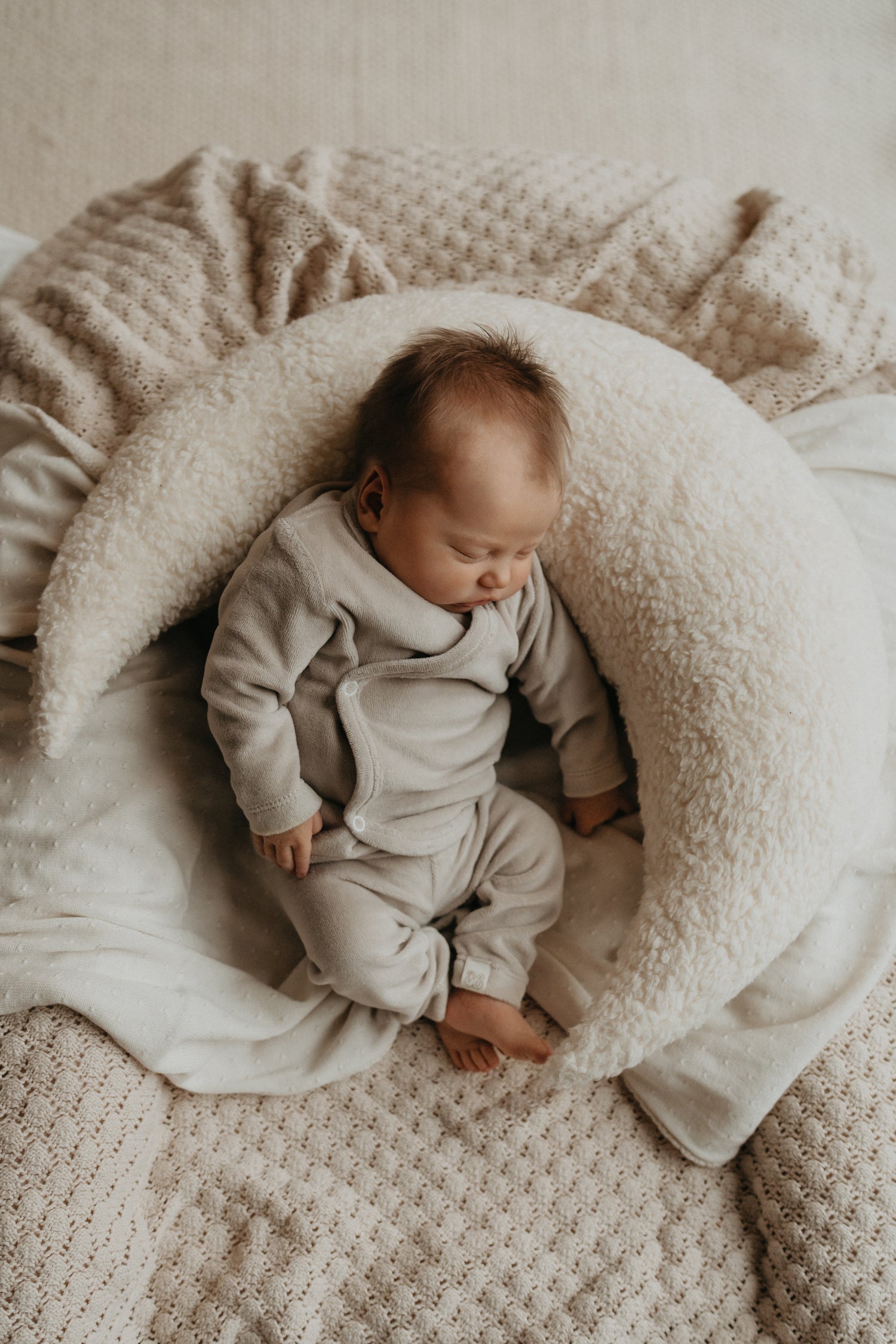 Geboortepakje beige fleece. Zacht en warm ligt de baby te slapen in een maankussen