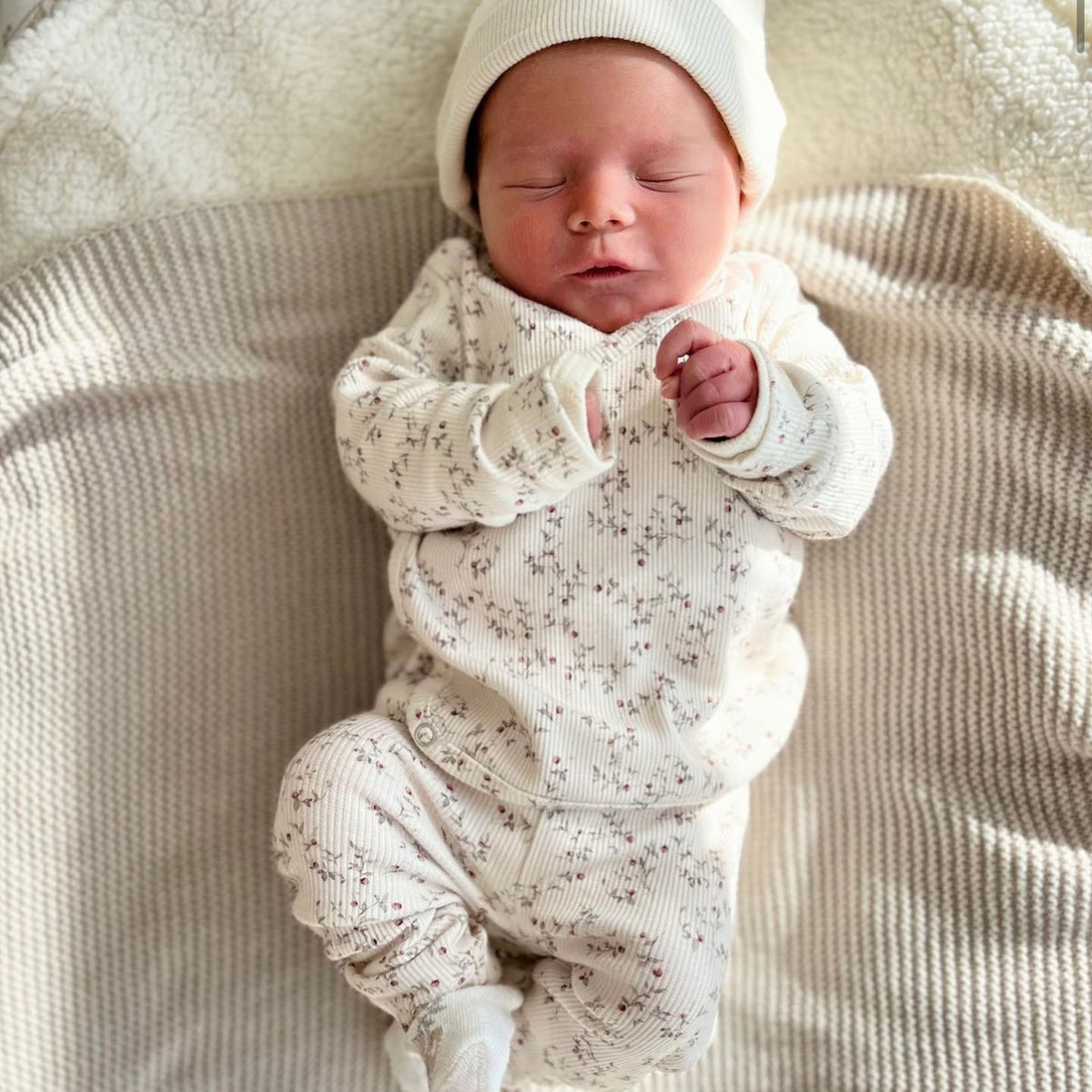 Vreedzame slaap: een pasgeboren baby slaapt stevig verpakt in warme tinten en gezellige texturen van OEKO-TEX gecertificeerde Osman Broekje Appeltakken, die onschuld en rust belichamen.