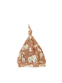 Een vredige pasgeboren baby gekleed in een rompertje met patroon en bijpassende Muts Boho Jungle, heerlijk slapend in een knus mandje omringd door zachte, crèmekleurige dekens.