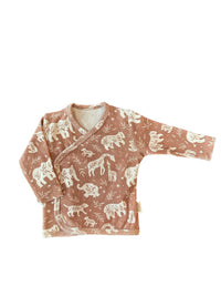 Een vredige pasgeboren baby slaapt knus in een geweven mand, gezellig gekleed in een Yumi Baby Boho Jungle overslagshirt en bijpassend mutsje, met zachte OEKO-TEX gecertificeerde katoenen dekens voor extra comfort.