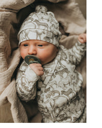 Een vredige pasgeborene, gezellig ingebakerd in een Zijdezacht Little Safari dekentje en outfitje, zuigt tevreden aan een speentje.