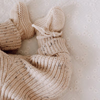 Een vredige baby slaapt heerlijk in een knus beige Yumi Baby Gebreide Set-outfit, met een zachte hoofdband en een klein knuffelkonijntje aan haar zijde.