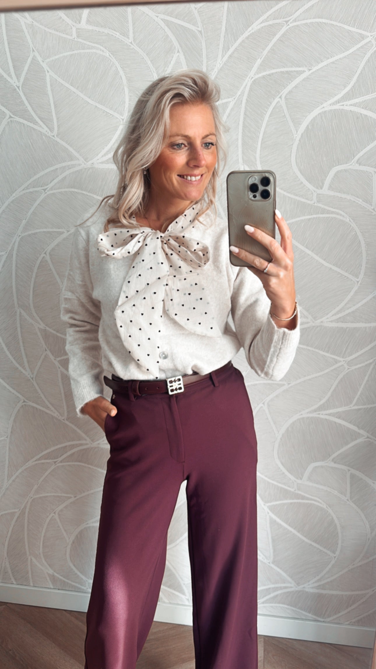 Model toont Off white vest met hartjes strik detail foto met burgundy pantalon 