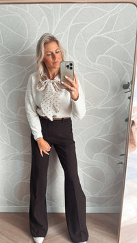 Model toont vooraanzicht van off white vest met strik met hartjes met bruine pantalon