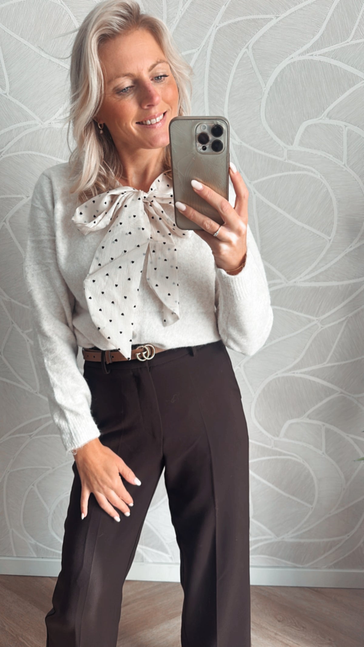 Model toont details van wit vest met hartjes strik met bruine pantalon