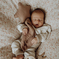Vreedzaam slapen: een tevreden baby dut met een speentje, lekker in een knusse trui en lekker geknuffeld door een Yumi Baby Knuffeldoekje Starlight.