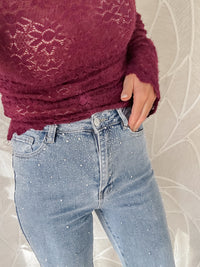 Model toont detail van licht blauwe stretch jeans met diamantjes