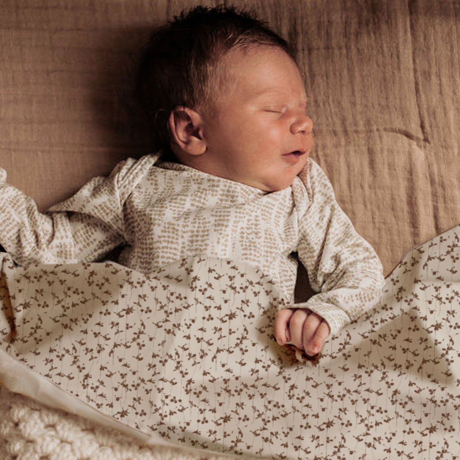 Vreedzame slaap: een pasgeboren baby gewikkeld in een Yumi Baby Wieglaken Brown Leafs dekentje, machinewasbaar voor eenvoudig onderhoud.