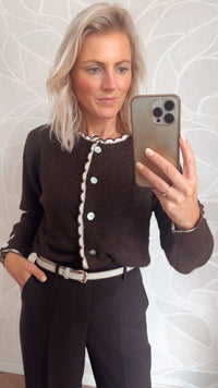 close-up bruin damesvest met witte scallop rand en parelknopen