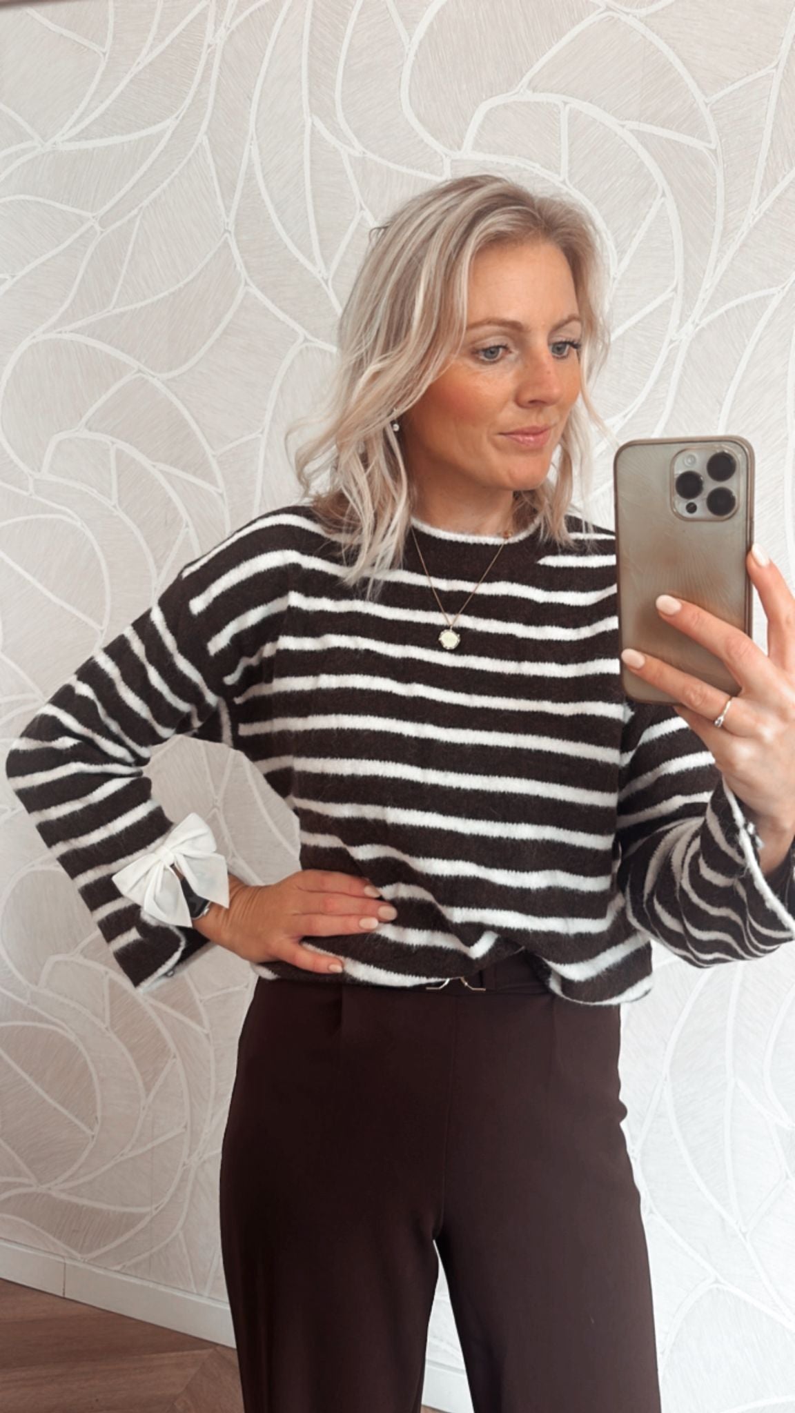 Model draagt bruine trui met beige strepen en strikdetail – stijlvolle herfsttrui van Yumi